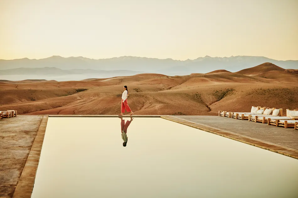 Extreme wide shot woman walking poolside at luxury desert camp.
Image used for illustrative purpose.
Image courtesy: Getty Images/ Thomas Barwick