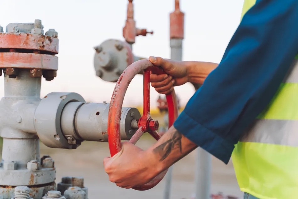 Pipeline equipment. Resource  transportation. Worker pumping down lines on the Gas drilling pad site. Disconnection or connection of gas or oil.
Image used for illustrative purpose.
Image courtesy: Getty Images/ Olga Rolenko